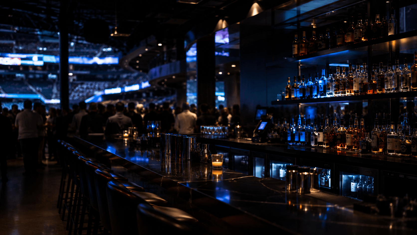 A stadium hospitality bar at night, back bar lit with electric-blue light